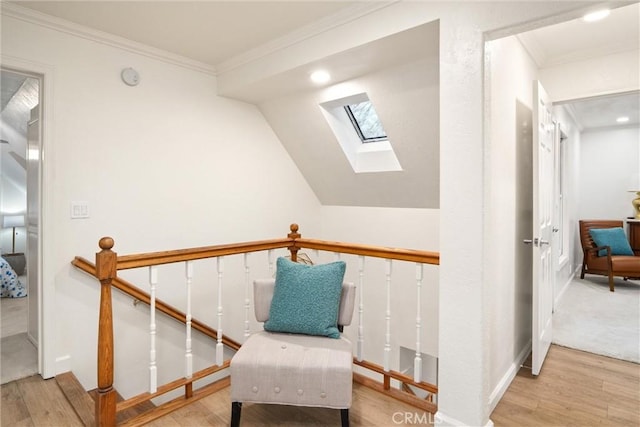 sitting room featuring crown molding, lofted ceiling with skylight, and light hardwood / wood-style floors