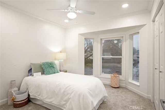 bedroom with crown molding, light carpet, ceiling fan, and a closet