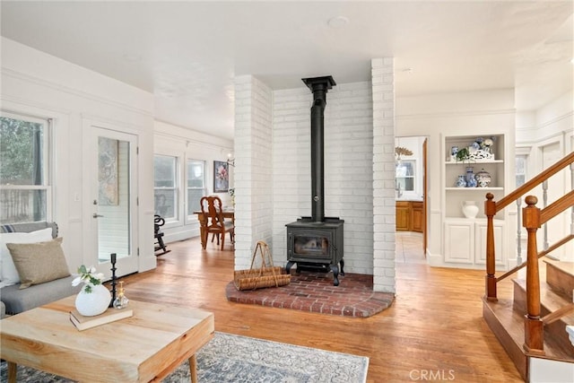 living room with plenty of natural light, a wood stove, and light hardwood / wood-style flooring