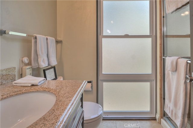 bathroom with vanity, tile patterned flooring, toilet, and a shower with door