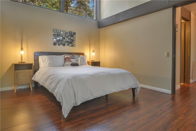 bedroom featuring a high ceiling and dark hardwood / wood-style floors