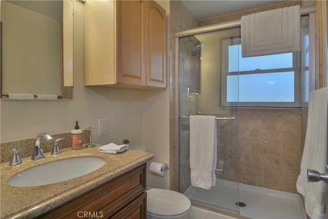 bathroom with a shower with door, vanity, and toilet