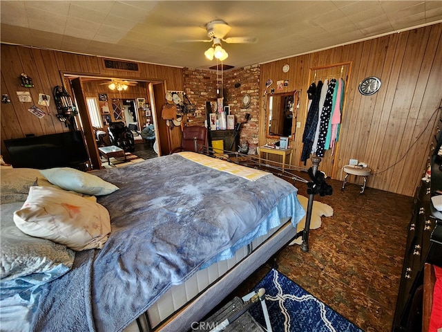 carpeted bedroom with ceiling fan and wood walls