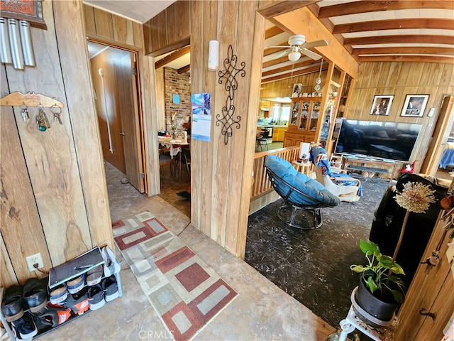 interior space with ceiling fan, vaulted ceiling with beams, and wood walls