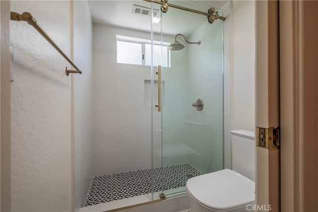 bathroom with a shower with shower door and toilet