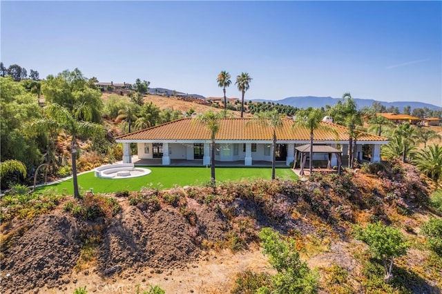 back of house with a mountain view and a lawn