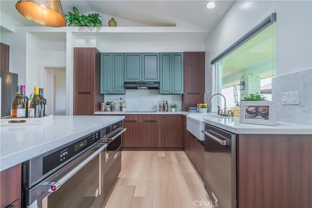 kitchen featuring dishwasher, lofted ceiling, sink, decorative backsplash, and light hardwood / wood-style floors