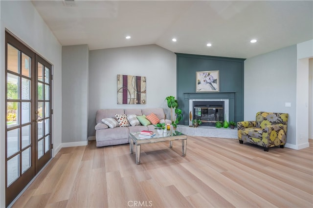 living room featuring lofted ceiling, light hardwood / wood-style floors, and french doors