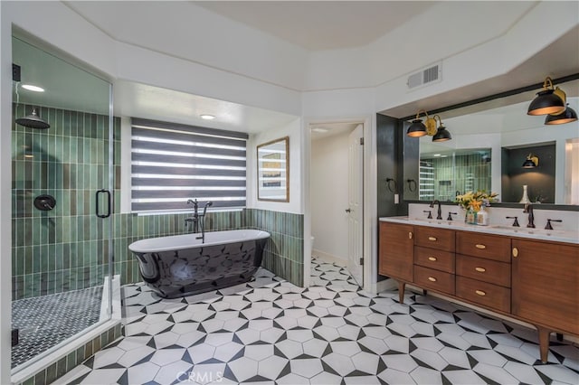 full bathroom featuring vanity, tile walls, independent shower and bath, and toilet