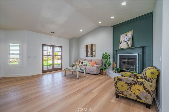 living area with vaulted ceiling, light hardwood / wood-style floors, and french doors