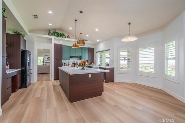 kitchen with a kitchen island, light hardwood / wood-style flooring, stainless steel refrigerator, and decorative light fixtures