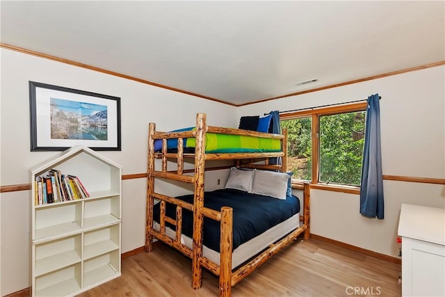 bedroom with ornamental molding and light hardwood / wood-style floors