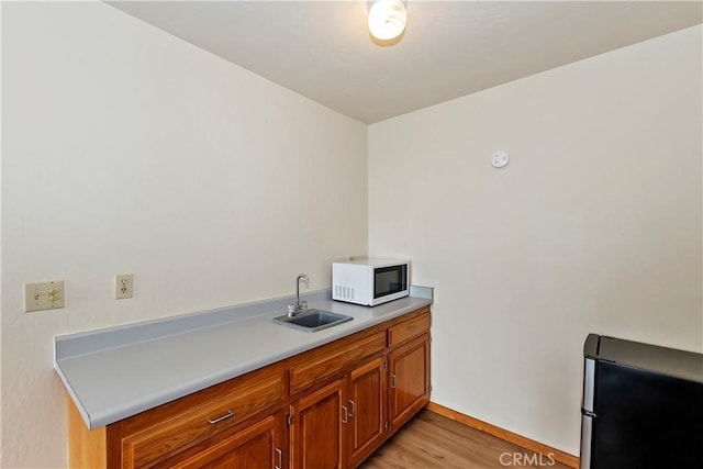 kitchen featuring light hardwood / wood-style flooring, stainless steel refrigerator, and sink