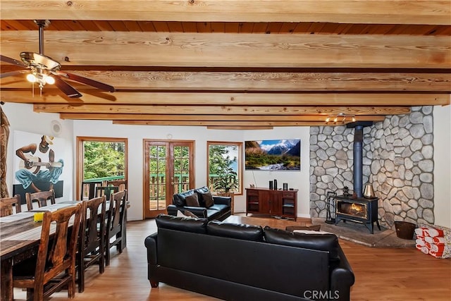 living room featuring a wood stove, ceiling fan, beam ceiling, and wooden ceiling