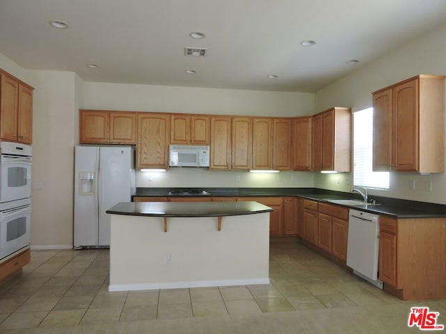 kitchen featuring a kitchen island, light tile patterned flooring, and white appliances