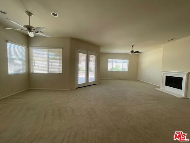 unfurnished living room with light colored carpet and ceiling fan