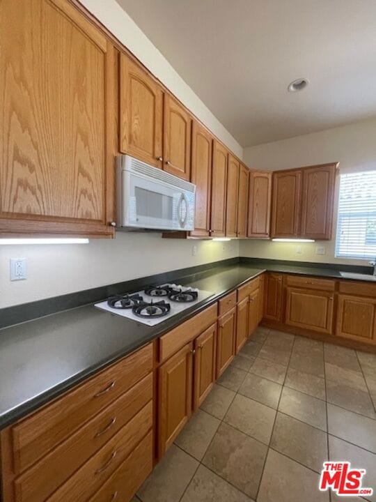 kitchen with sink, light tile patterned floors, and white appliances