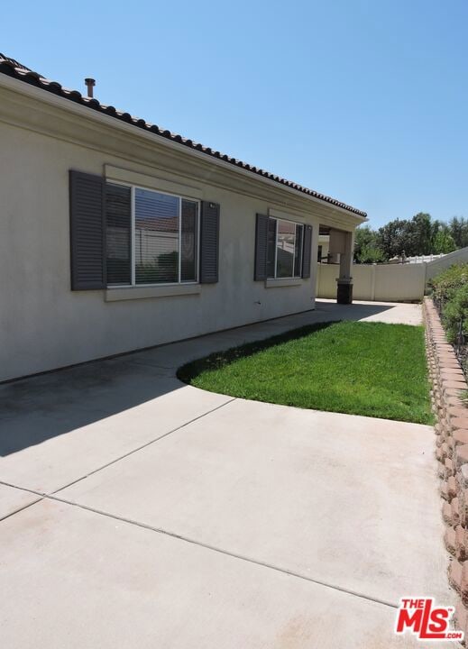 view of side of home featuring a patio area and a lawn