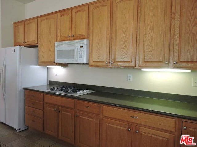 kitchen featuring dark tile patterned floors and white appliances