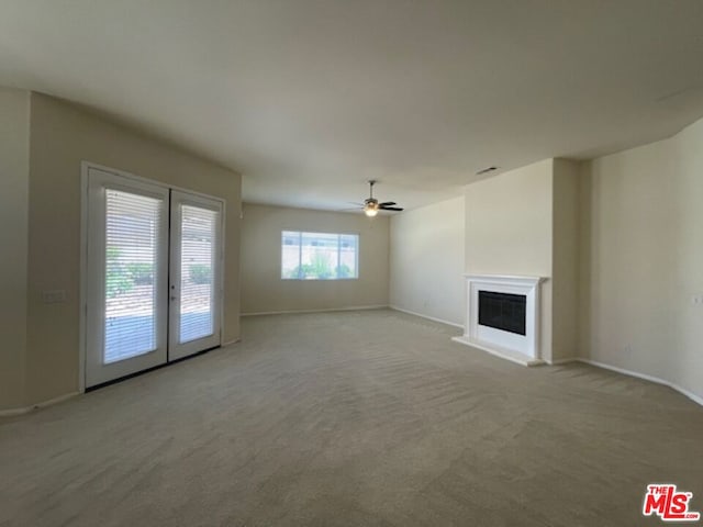 unfurnished living room featuring french doors, light carpet, and ceiling fan