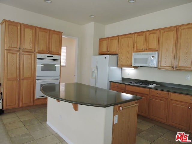 kitchen featuring a center island, light tile patterned floors, and white appliances