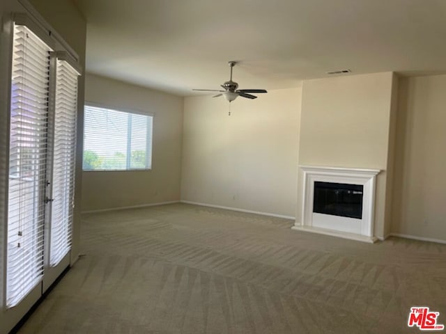 unfurnished living room with carpet, french doors, and ceiling fan