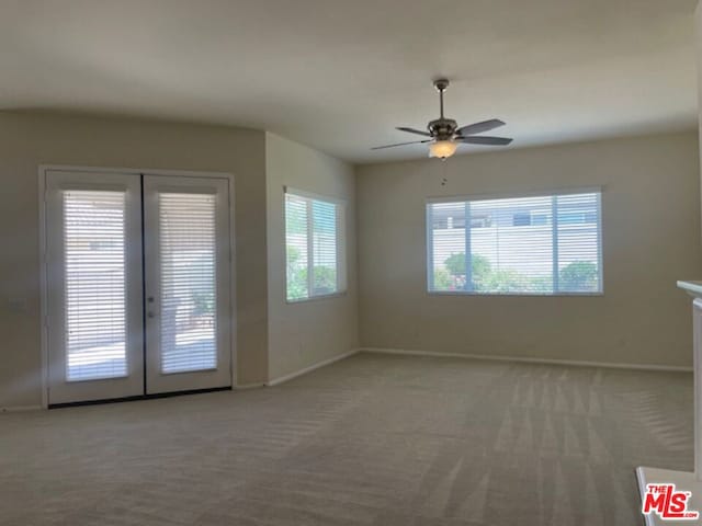 carpeted spare room featuring french doors and ceiling fan