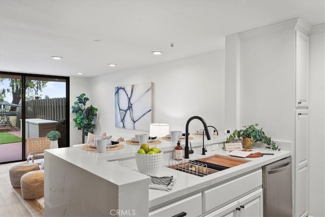 kitchen with expansive windows, white cabinets, sink, light stone countertops, and light hardwood / wood-style floors