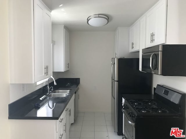 kitchen featuring white cabinetry, sink, light tile patterned floors, and appliances with stainless steel finishes