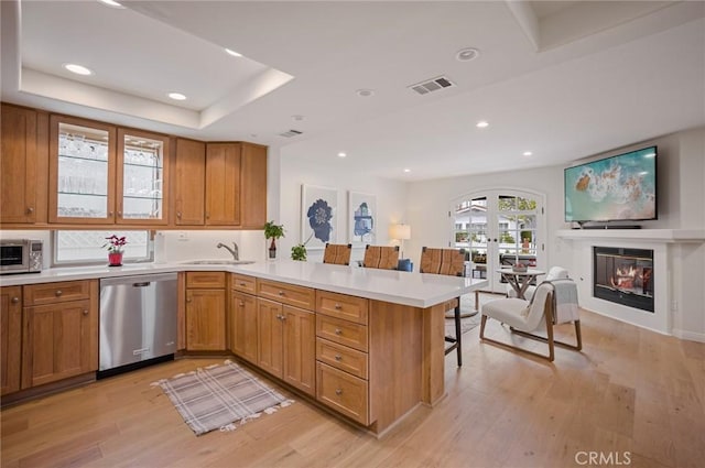 kitchen featuring sink, light hardwood / wood-style flooring, appliances with stainless steel finishes, a kitchen bar, and kitchen peninsula