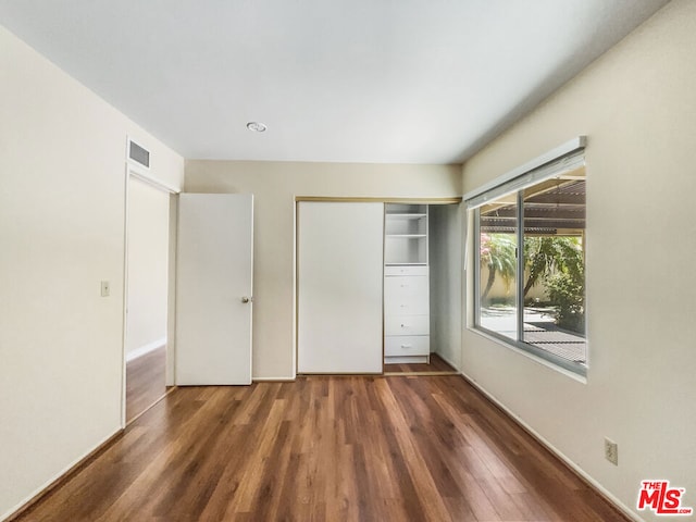 unfurnished bedroom featuring dark hardwood / wood-style floors and a closet