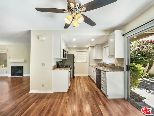 kitchen with dark stone counters, sink, dark hardwood / wood-style floors, appliances with stainless steel finishes, and white cabinetry