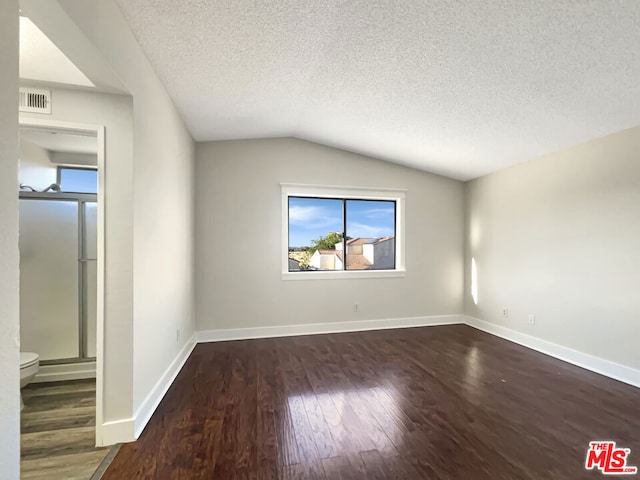 unfurnished room featuring a textured ceiling, lofted ceiling, and dark hardwood / wood-style floors