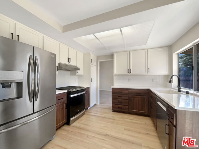 kitchen with appliances with stainless steel finishes, white cabinetry, light hardwood / wood-style flooring, dark brown cabinetry, and sink