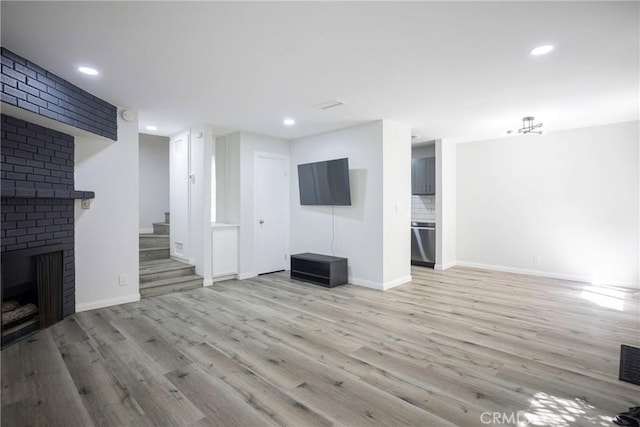 unfurnished living room with a brick fireplace and light hardwood / wood-style flooring