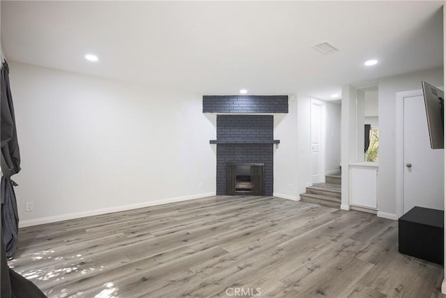 unfurnished living room featuring a fireplace and light hardwood / wood-style floors