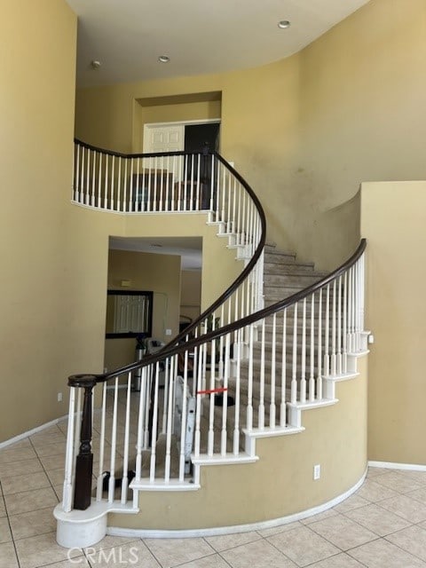 stairway featuring a towering ceiling and tile patterned flooring