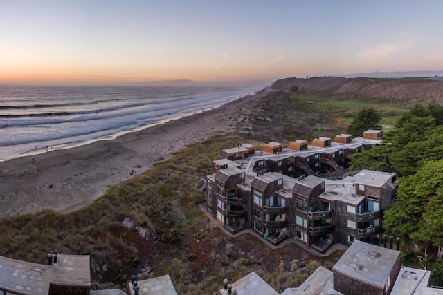 aerial view at dusk with a water view and a beach view