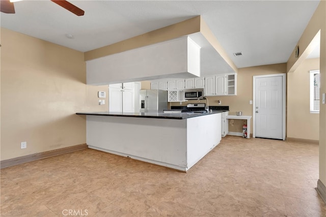 kitchen with kitchen peninsula, ceiling fan, stainless steel appliances, and white cabinets