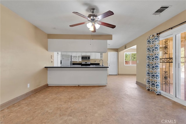 kitchen featuring white cabinets, kitchen peninsula, stainless steel appliances, ceiling fan, and sink