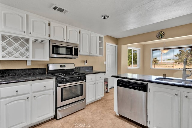 kitchen with sink, a textured ceiling, decorative light fixtures, white cabinetry, and appliances with stainless steel finishes