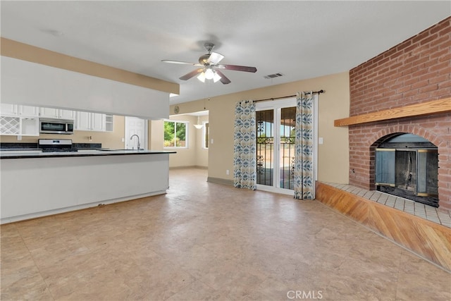 unfurnished living room with light wood-type flooring, a fireplace, sink, and ceiling fan