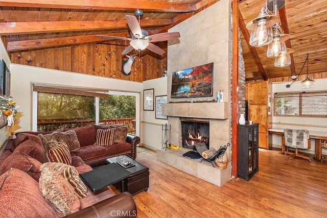 living room with wooden ceiling, a tiled fireplace, ceiling fan, hardwood / wood-style flooring, and lofted ceiling with beams