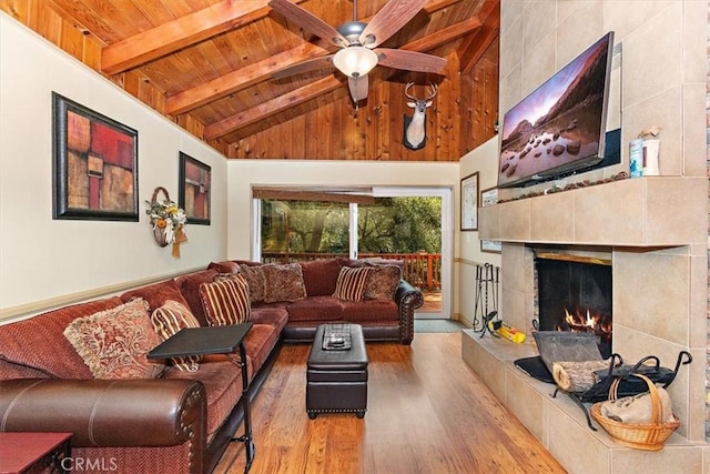 living room featuring a tiled fireplace, wood ceiling, light wood-type flooring, and beamed ceiling