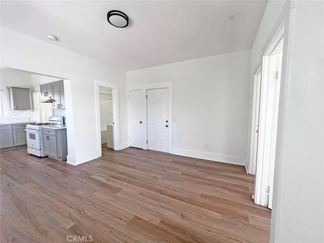 unfurnished bedroom featuring wood finished floors, connected bathroom, and baseboards