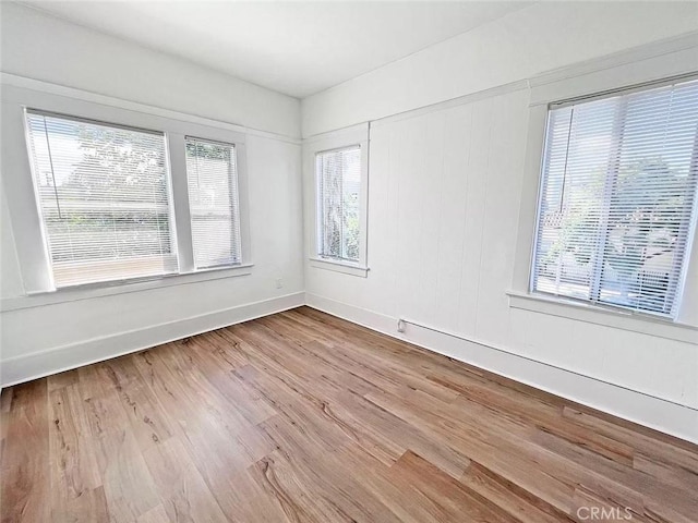 spare room featuring light wood-type flooring and baseboards