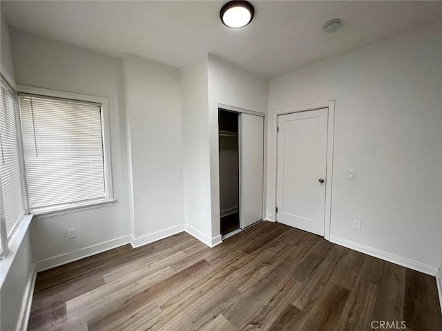 unfurnished bedroom with a closet, baseboards, and wood finished floors