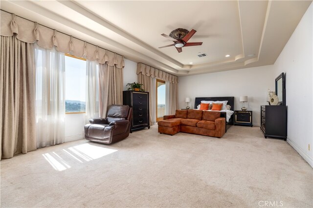 carpeted bedroom featuring ceiling fan and a tray ceiling