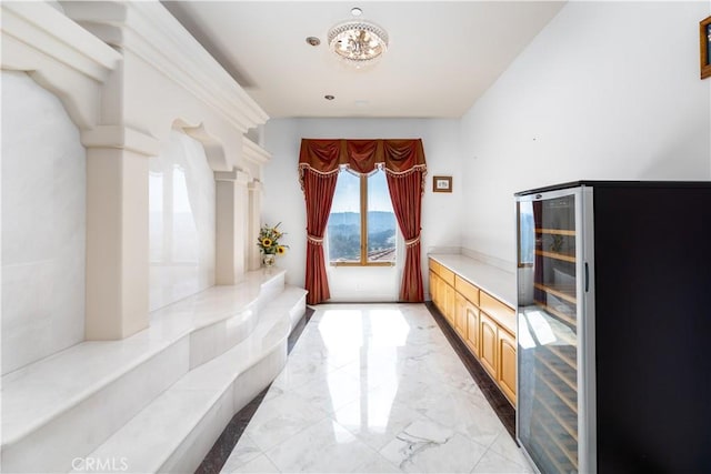 mudroom with beverage cooler, a chandelier, and decorative columns