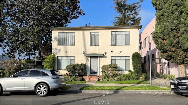 view of front of property featuring stucco siding and fence